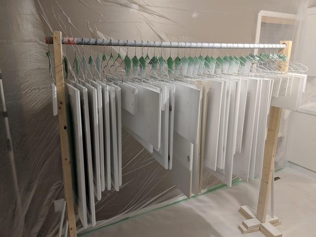 Freshly sprayed white cabinet doors hanging on a custom drying rack