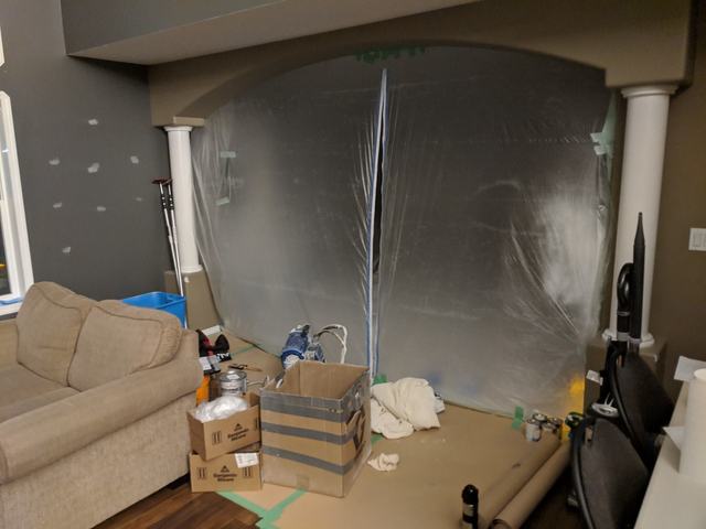 Living room with a plastic zip-wall containing the work area and floors protected